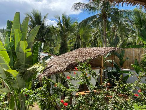 a hut with a thatched roof in a garden at Parrots Boutique Resort in San Vicente