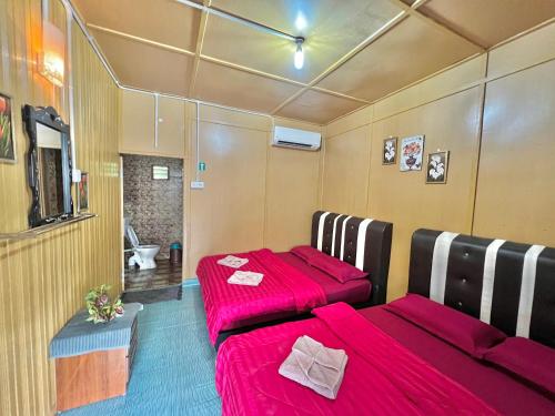 2 Betten in einem Zimmer mit roter Bettwäsche in der Unterkunft Perhentian Sri Tanjung , Pulau Perhentian in Perhentian Island