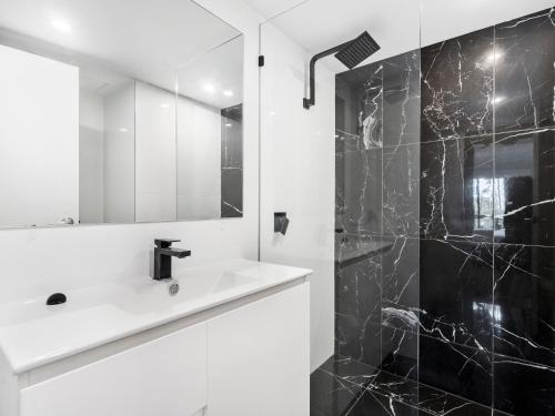 a black and white bathroom with a sink and a mirror at Luxury Stunning Nobby's Beach Home 2bd + Den ! in Gold Coast