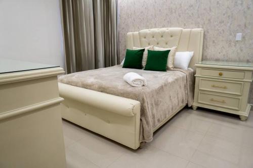 a bedroom with a bed with green and white pillows at Livera in Santiago de los Caballeros