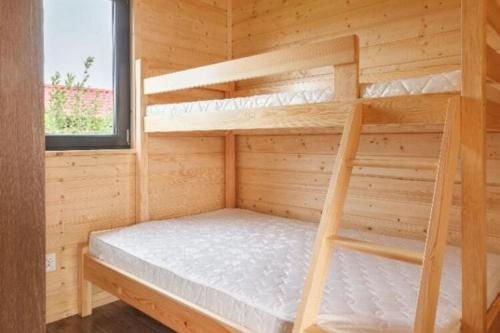 a bedroom with bunk beds in a wooden cabin at One-storey holiday houses near the beach, G ski in Gąski