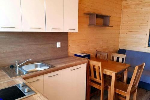 a kitchen with a sink and a table with chairs at One-storey holiday houses near the beach, G ski in Gąski