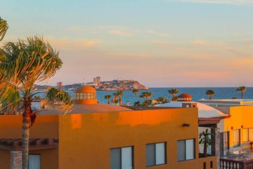 a building with a palm tree in front of the ocean at LUX 3 MASTER BDROOM ON SANDY BEACH w NO CLEAINING FEE in Puerto Peñasco
