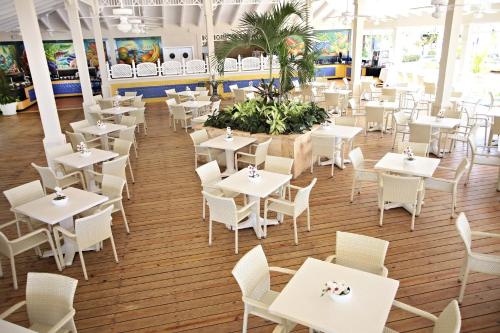 an empty restaurant with white tables and chairs at Bahia Principe Grand La Romana - All Inclusive in La Romana