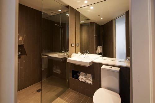 a bathroom with a sink and a toilet and a mirror at Rydges Sydney Airport Hotel in Sydney