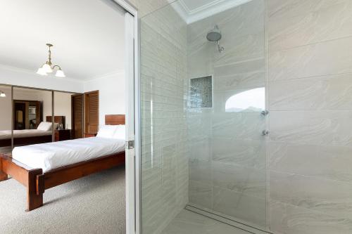 Una ducha de cristal en un dormitorio con cama. en Friendship Key, en Forster