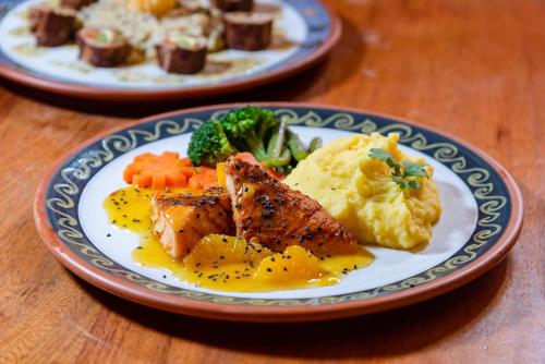 zwei Teller mit Fleisch und Gemüse auf einem Tisch in der Unterkunft Hotel Pakaritampu in Ollantaytambo