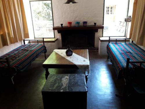 een kamer met 2 bedden, een tafel en een open haard bij La Rosadita del Paraje in Villa Yacanto