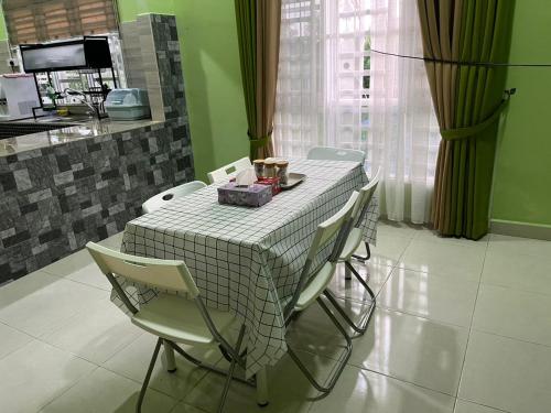 einem Tisch mit Stühlen und einem weißen und grauen Tischtuch in der Unterkunft D'Rhu Homestay with 2 aircond in Bachok