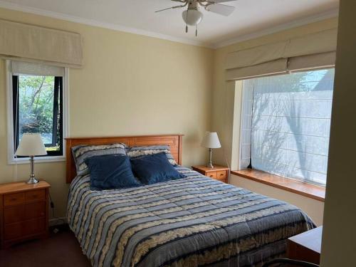 a bedroom with a bed with blue pillows and a window at Acogedora casa en Pingueral in Concepción