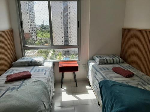 two beds sitting in a room with a window at Apartamento completo in Manaus
