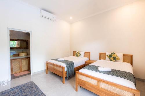 a room with two beds and a cabinet in it at Kubu Kirana by Supala in Ubud