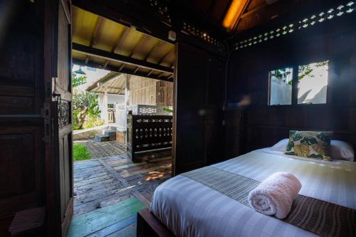 Schlafzimmer mit einem Bett auf einer Holzterrasse in der Unterkunft Kubu Kirana by Supala in Ubud