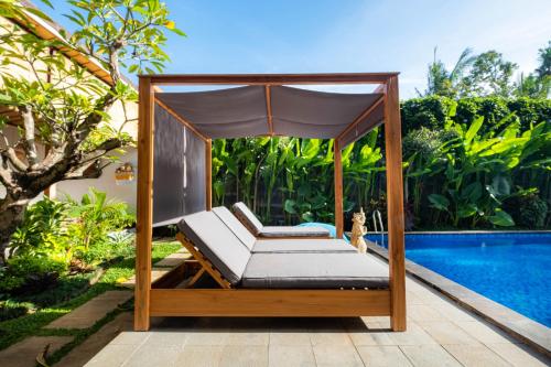 a bed with a canopy next to a pool at Kubu Kirana by Supala in Ubud