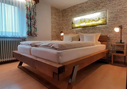 a large bed in a room with a brick wall at Hotel - Pension - Heidelberg inkl. Chiemgaukarte in Ruhpolding
