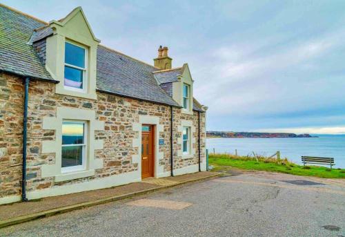 a stone cottage with a view of the water at Hill Crest - cliff top cottage with stunning views in Cullen