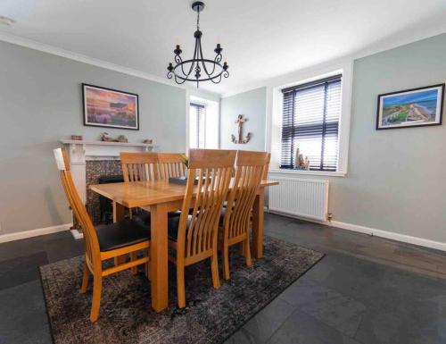 a dining room with a wooden table and chairs at Hill Crest - cliff top cottage with stunning views in Cullen