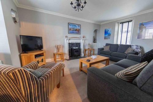 a living room with two couches and a television at Hill Crest - cliff top cottage with stunning views in Cullen