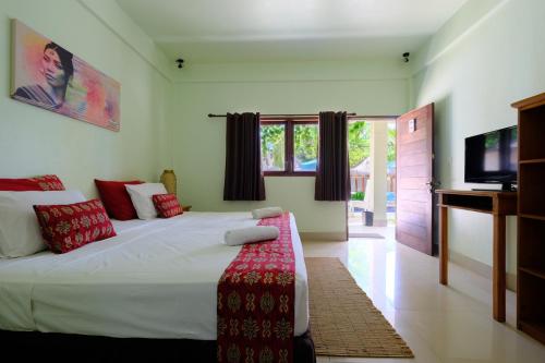 a bedroom with a large bed and a television at Trawangan Nirvana in Gili Trawangan