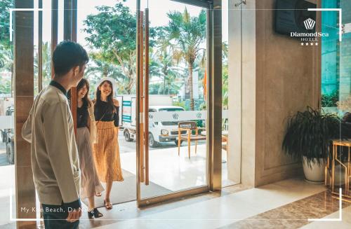 a man standing in front of a door with two women at Diamond Sea Hotel in Da Nang