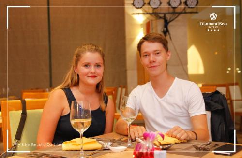 a man and a woman sitting at a table with wine glasses at Diamond Sea Hotel in Da Nang