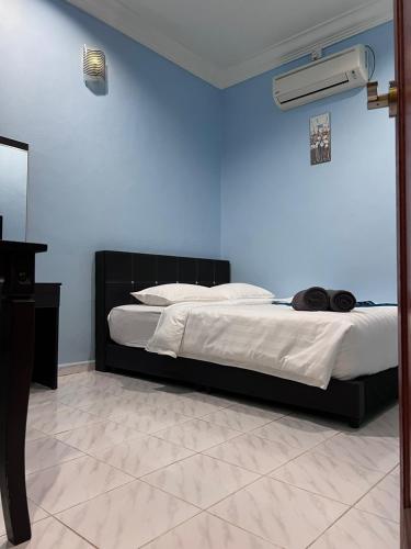 a bedroom with a bed with a blue wall at HOTEL RAUDHAH Kerteh in Kertih
