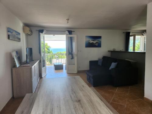 a living room with a couch and a sliding glass door at Villa OCÉAN chez R'marine439 locations saisonnières in Sainte-Rose