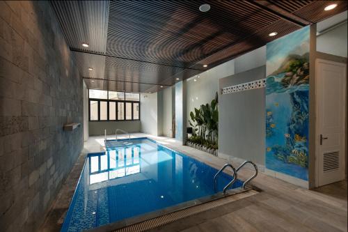 a swimming pool in a room with a large at Mercury Beach DaNang in Danang