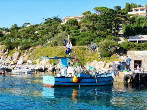 un bateau bleu est amarré dans l'eau dans l'établissement RC d'un Cabanon écologique ile du levant Naturiste, sur l'Île du Levant