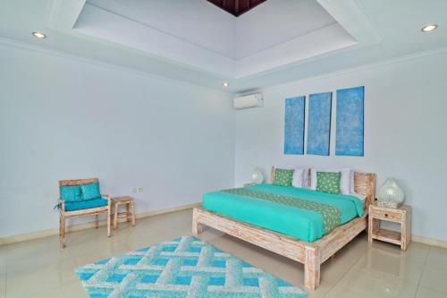 a bedroom with a bed and a table and a chair at Villa Alam Biru in Sanur