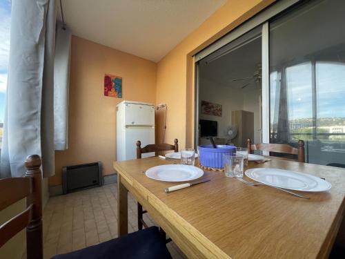 une table en bois avec deux plaques blanches au-dessus dans l'établissement Studio cabine avec loggia vitrée, à 100m de la plage, proche commerces et activités à Sète - FR-1-338-492, à Sète