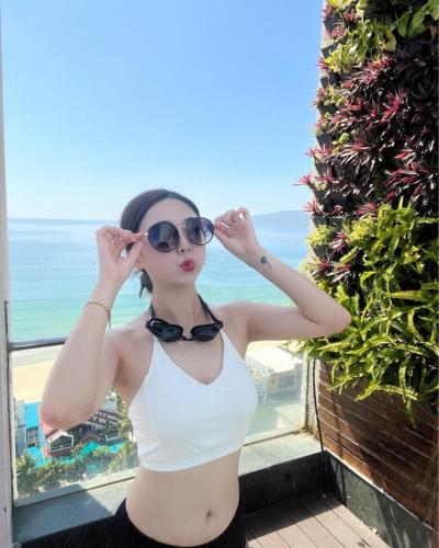 a woman in a white bikini and sunglasses at Diamond Sea Hotel in Da Nang