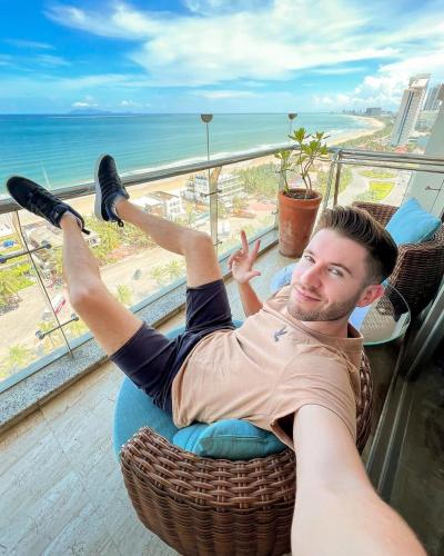 a man laying in a chair in front of a window at Diamond Sea Hotel in Da Nang