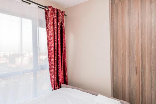 a bedroom with a red curtain and a window at StayEasy Tsavo in Nairobi