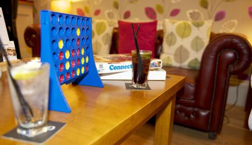 a table with a game of dominoes and a drink at Strawberry Bank Hotel, NEC in Meriden