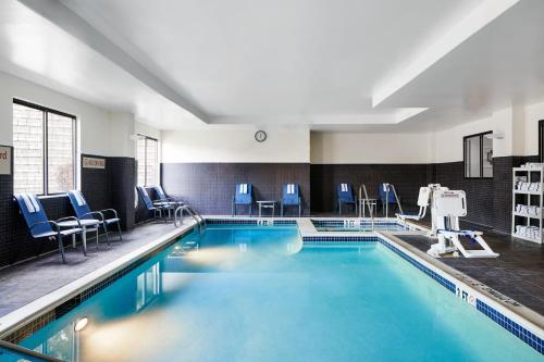 a swimming pool with blue chairs in a building at TownePlace Suites by Marriott Harrisburg Hershey in Harrisburg