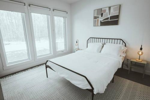 a white bedroom with a large bed and windows at NYC Loft Inspired •12 mins to WEM •Vintage arcade in Edmonton