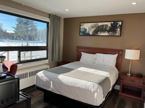 a bedroom with a bed and a large window at Champlain Motor Inn in Pembroke