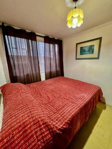 a bedroom with a bed with a red comforter and a window at Casa de veraneo in Los Vilos