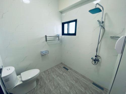 a white bathroom with a toilet and a window at 舞艾湖民宿 in Hsing-wen