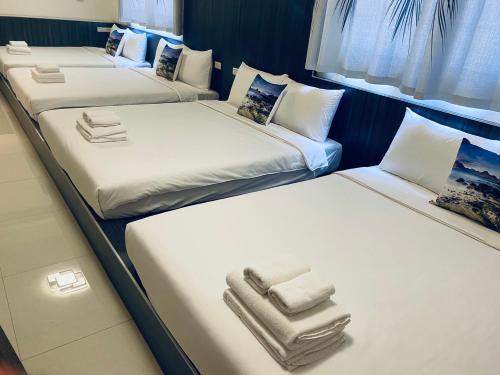 three beds in a room with white sheets and towels at 舞艾湖民宿 in Hsing-wen