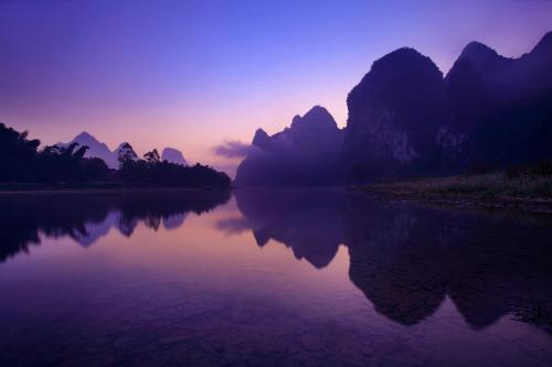 a view of a river at sunset with mountains at Li-river Island Resort Xingping Yangshuo in Yangshuo