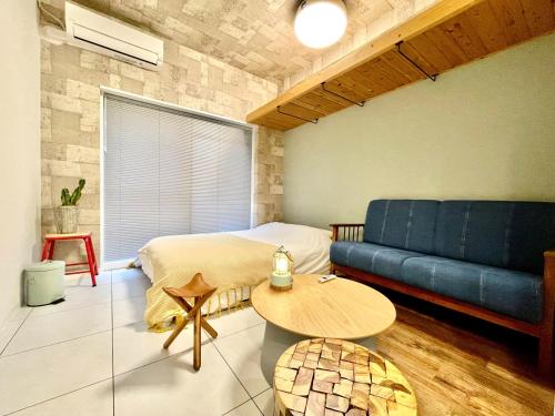ein Schlafzimmer mit einem Bett und einem blauen Sofa in der Unterkunft 365BASE outdoor hostel in Hamamatsu