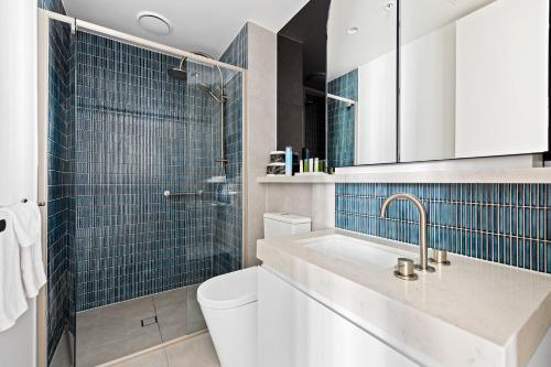 y baño con lavabo, aseo y azulejos azules. en The Marker Apartments Melbourne en Melbourne