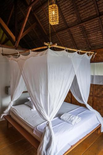 a bed in a room with a mosquito net at Casa Nemo Beach Resort & Spa in Sabong