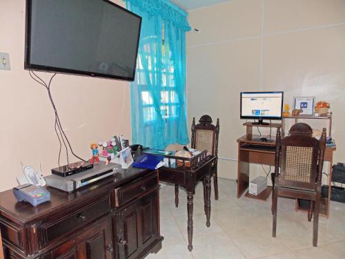 a living room with a desk with a television on it at Pousada Pedacinho de Céu in Abraão