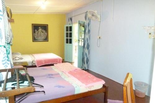 a room with two beds in a room with yellow walls at Cheers Garden Chalet in Kampung Tekek