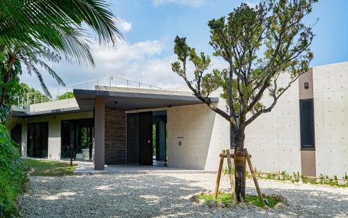 ein Haus mit einem Baum davor in der Unterkunft Villa El Cielo Ishigaki in Ishigaki-jima