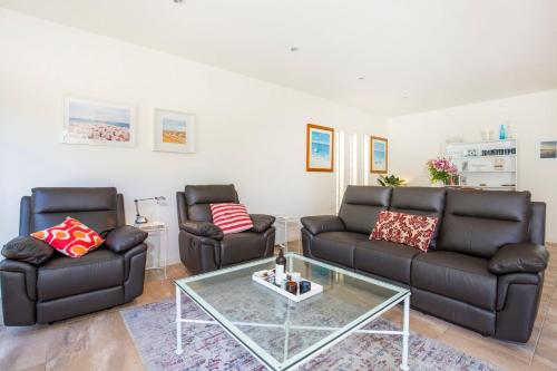a living room with two leather couches and a glass table at Thalassa I Pet Friendly I 2 Mins Walk to Beach in Culburra Beach