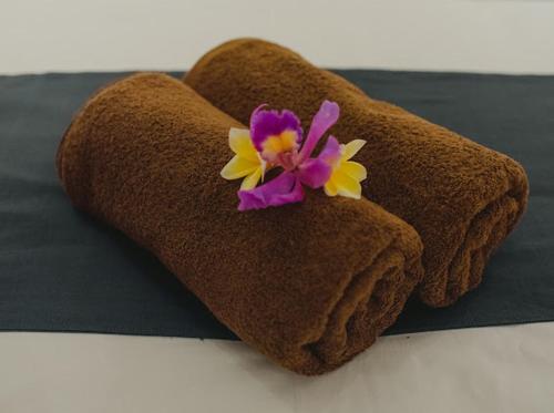 a brown towel with a flower on top of it at Pandu guest house in Ubud